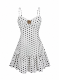 White spaghetti-strap mini dress with black polka dots and a gold starburst brooch at the bust, shown on a plain white background.
