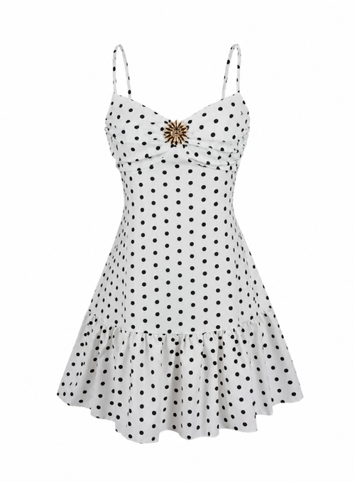 White spaghetti-strap mini dress with black polka dots and a gold starburst brooch at the bust, shown on a plain white background.