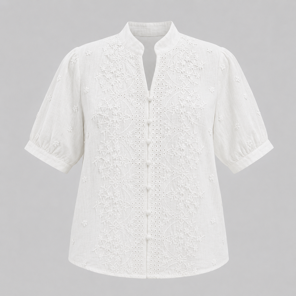 White short-sleeve eyelet blouse with a mandarin collar and button front, shown on a neutral gray background.