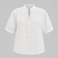 White short-sleeve eyelet blouse with a mandarin collar and button front, shown on a neutral gray background.