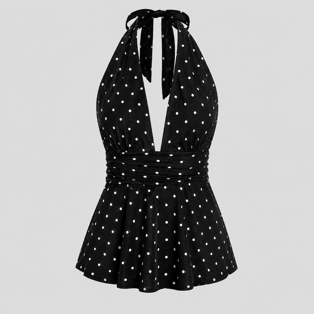 A black halter-neck dress with white polka dots, featuring a tie-front neckline, a gathered waist, and a flared skirt, shown against a solid light gray background.